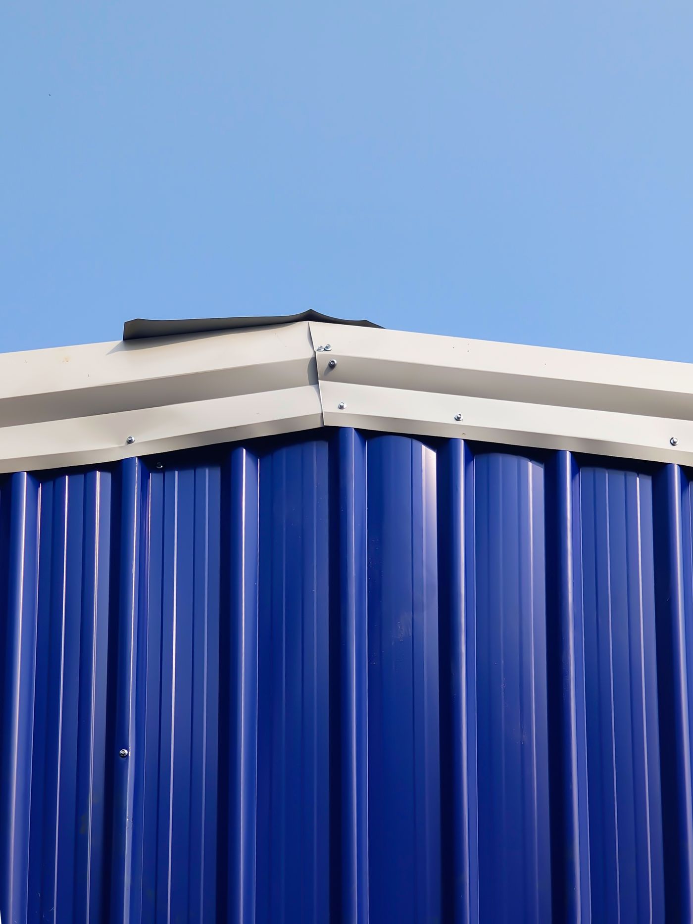 Blue metal cladding and roof edge against sky